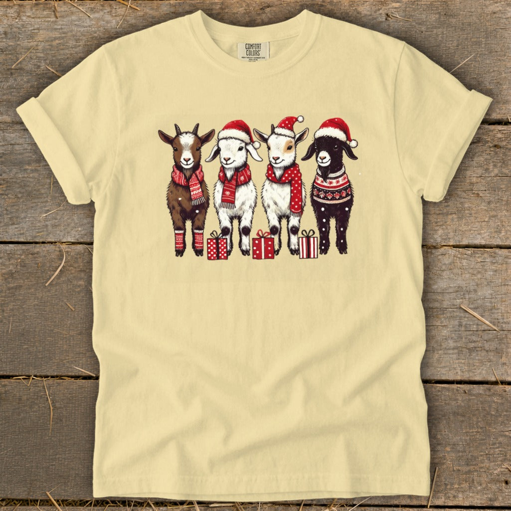 Four goats in festive attire stand with presents on a light yellow t-shirt.