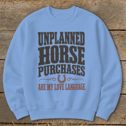 Light blue sweatshirt with "Unplanned Horse Purchases Are My Love Language" text and horseshoe graphic.