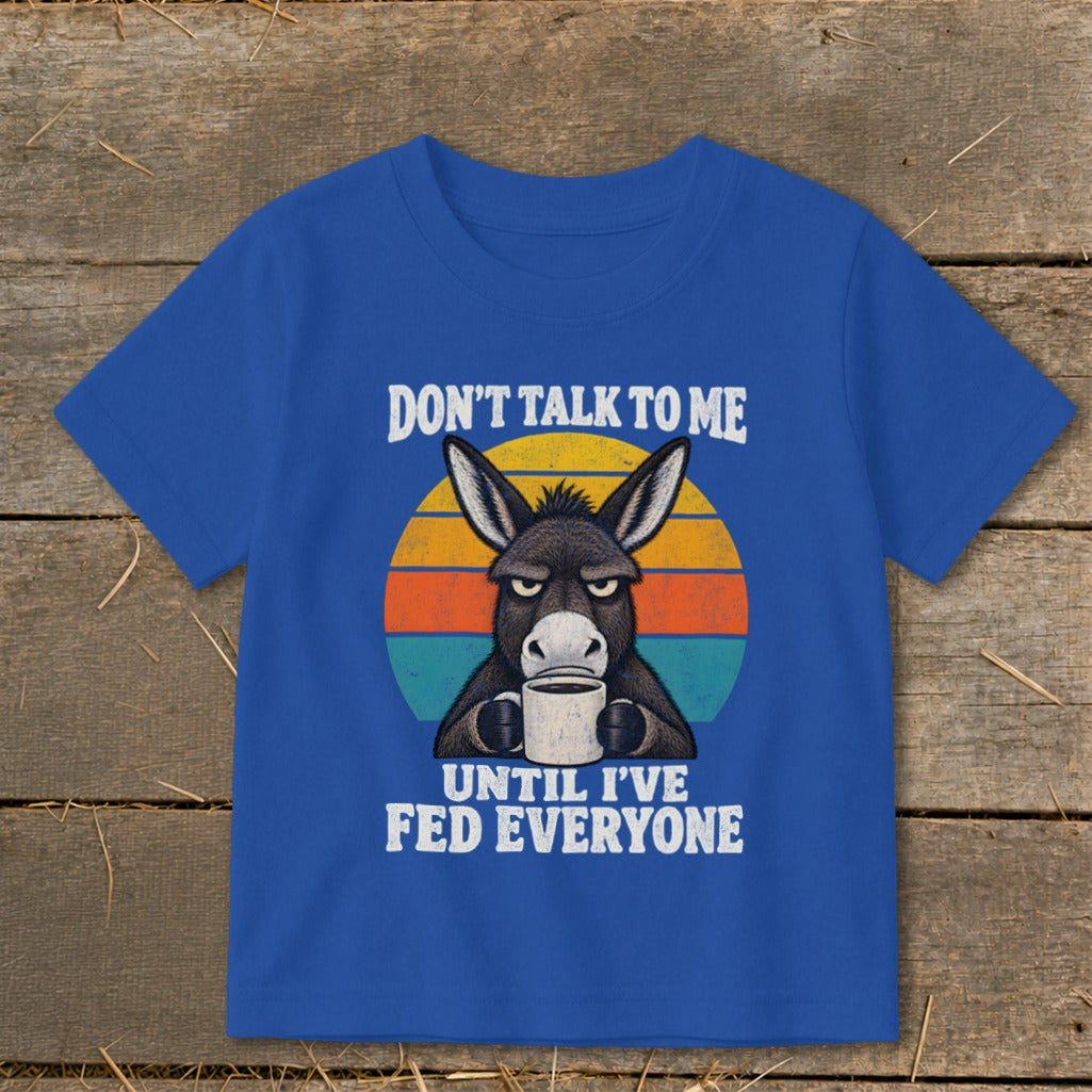 Royal blue t-shirt featuring an illustration of an annoyed donkey holding a coffee mug, overlaid on a sunset graphic with text reading "Don't Talk To Me Until I've Fed Everyone".