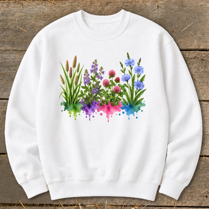A white crewneck sweatshirt features a central graphic of colorful wildflowers emerging from watercolor splashes.