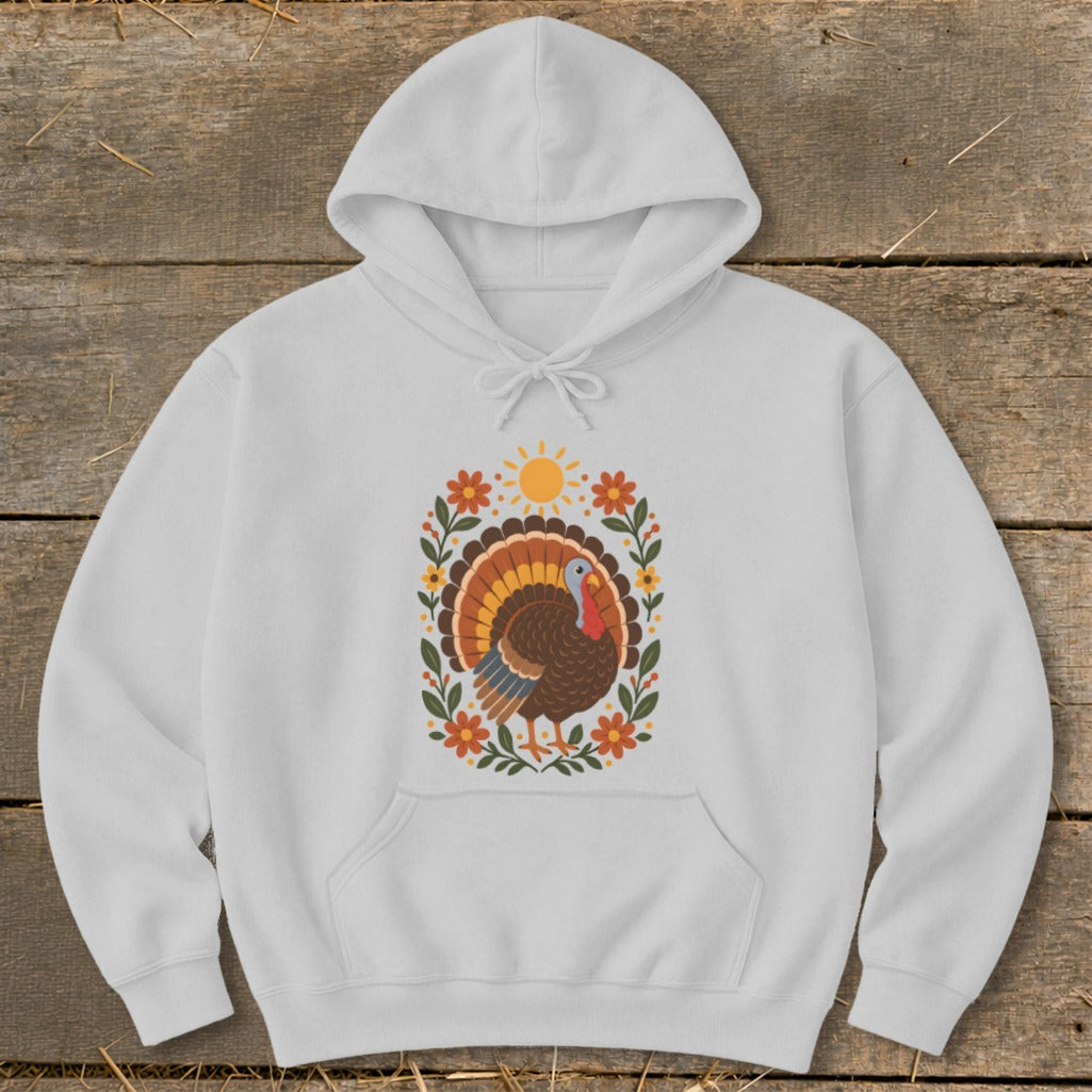 White hoodie with a decorative turkey, sun, and floral wreath graphic.