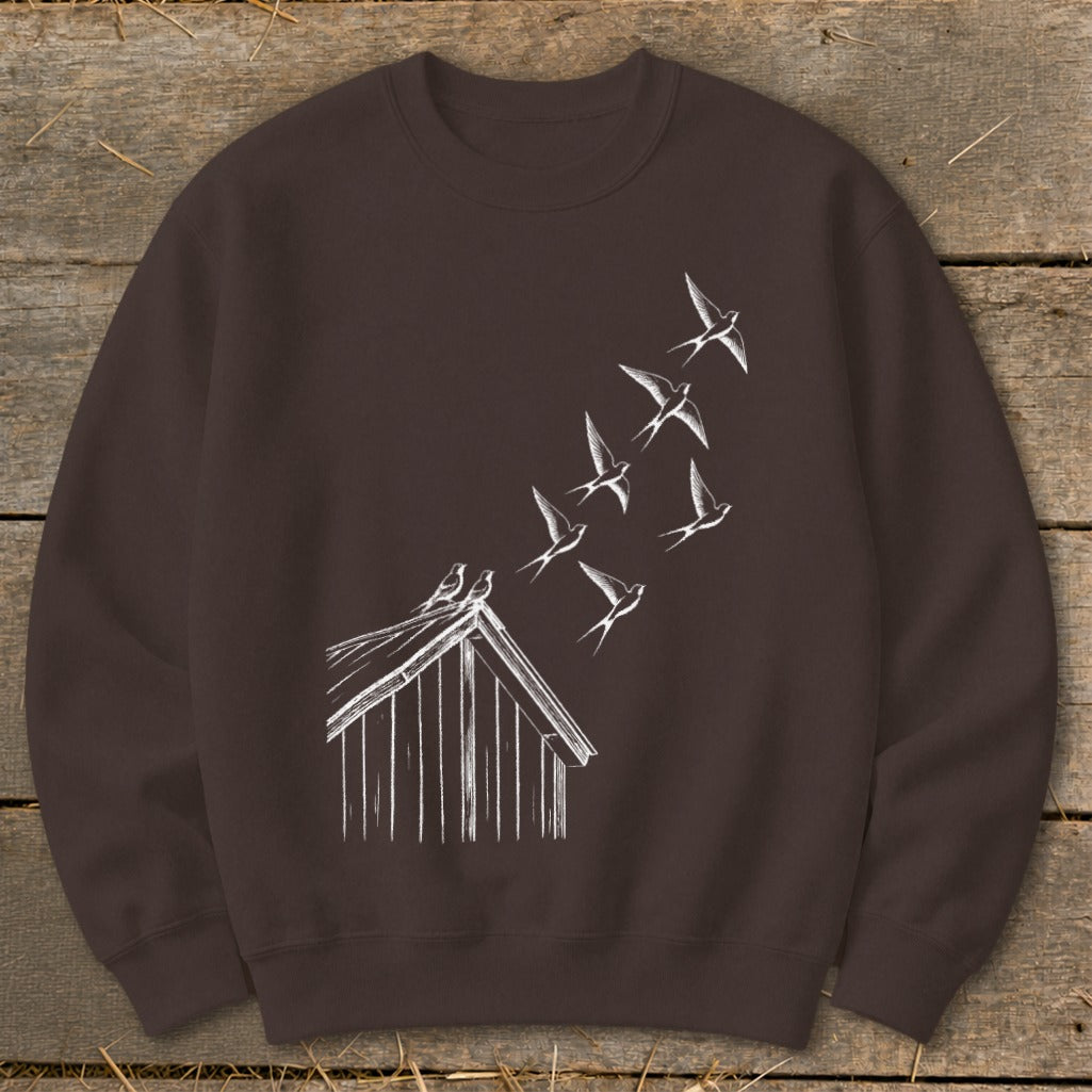 A dark brown crewneck sweatshirt featuring a white sketch graphic of birds flying up from a shed roof.