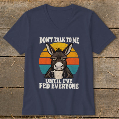 Dark blue V-neck t-shirt featuring a grumpy donkey holding a coffee mug with the text Don't Talk to Me Until I've Fed Everyone.