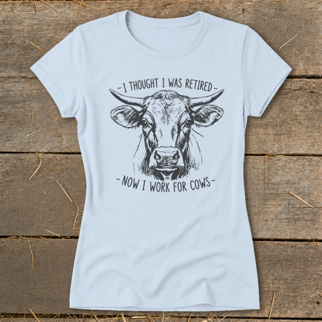 Light blue t-shirt with a sketch of a cow and text "-I thought I was retired- -now I work for cows-".