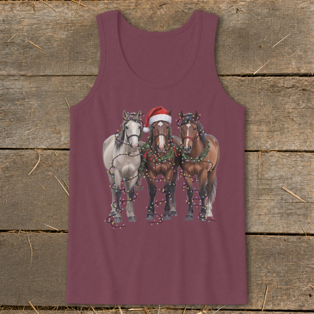 Three horses, one wearing Santa hat, decorated with Christmas lights and wreaths.