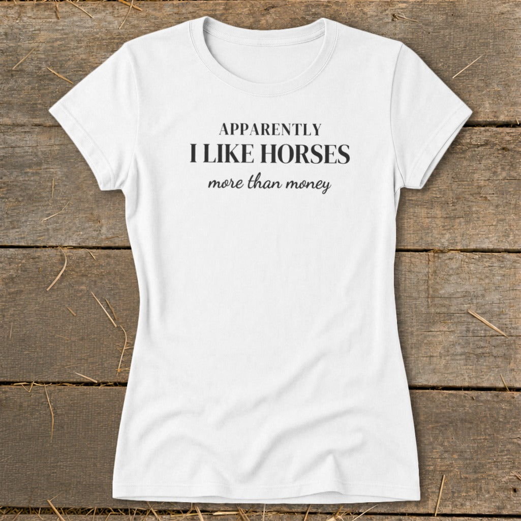 White t-shirt with black text that reads "APPARENTLY I LIKE HORSES more than money".
