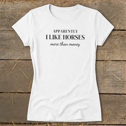 White t-shirt with black text that reads "APPARENTLY I LIKE HORSES more than money".