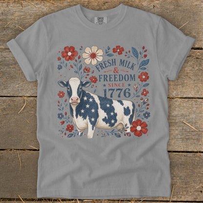 Cow with American flag pattern surrounded by flowers, text reads "Fresh Milk & Freedom Since 1776".
