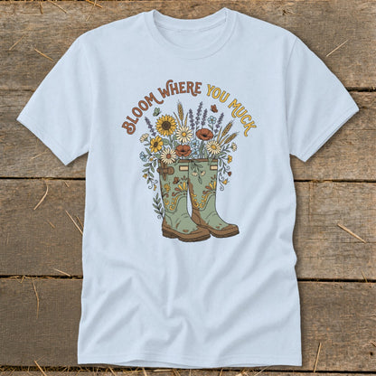 Light blue t-shirt with green boots and floral design, text says "Bloom Where You Muck".