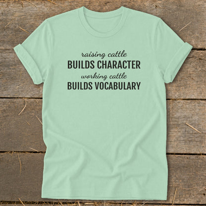 Light mint t-shirt with black text: "raising cattle BUILDS CHARACTER working cattle BUILDS VOCABULARY".