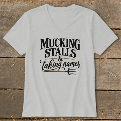 Light gray v-neck t-shirt with "Mucking Stalls & Taking Names" text and a pitchfork.