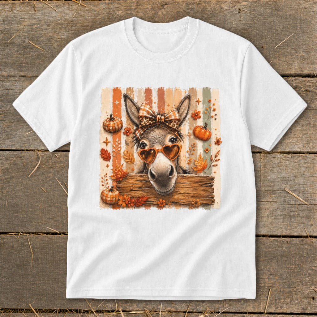 Donkey wearing heart sunglasses and bow, surrounded by pumpkins and autumn leaves.