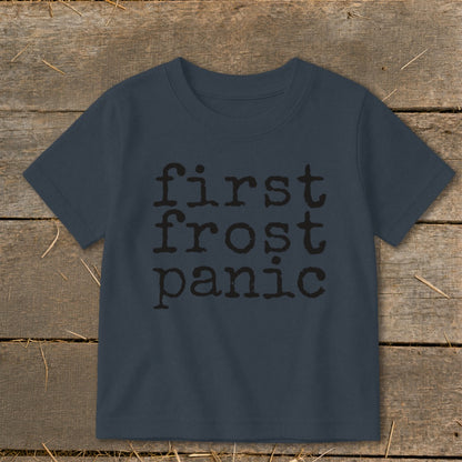 Navy t-shirt with black text "first frost panic" on a wooden background.