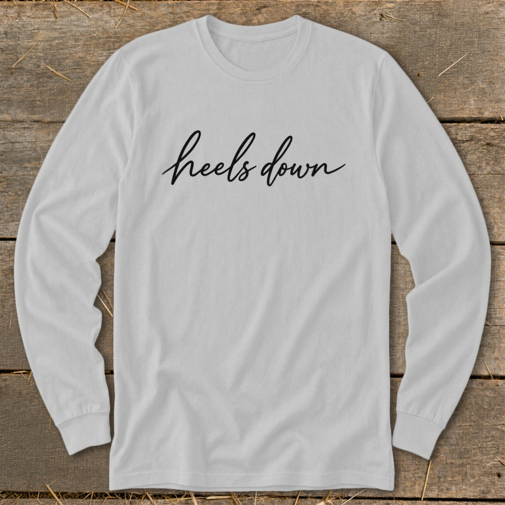 White long-sleeved shirt with "heels down" in black cursive text.