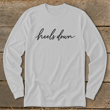 White long-sleeved shirt with "heels down" in black cursive text.