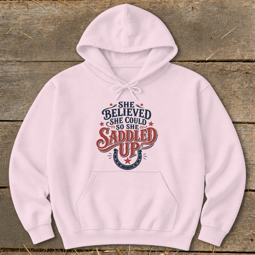 Pink hoodie with "She believed she could so she saddled up" text and horseshoe graphic.