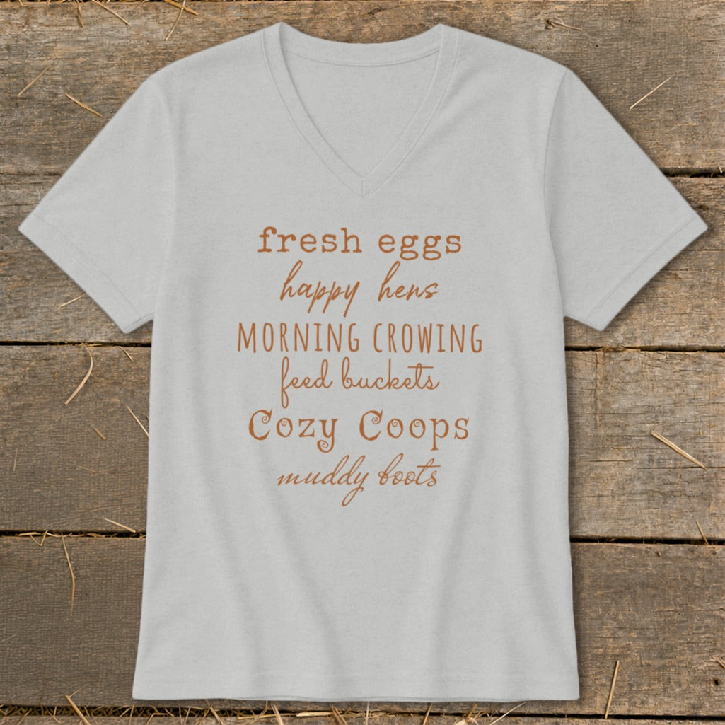 Light gray v-neck t-shirt with "fresh eggs happy hens MORNING CROWING feed buckets Cozy Coops muddy boots" text.
