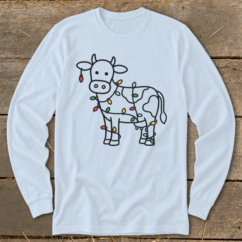Light blue long sleeve shirt with a black outline drawing of a cow adorned with colorful Christmas lights.