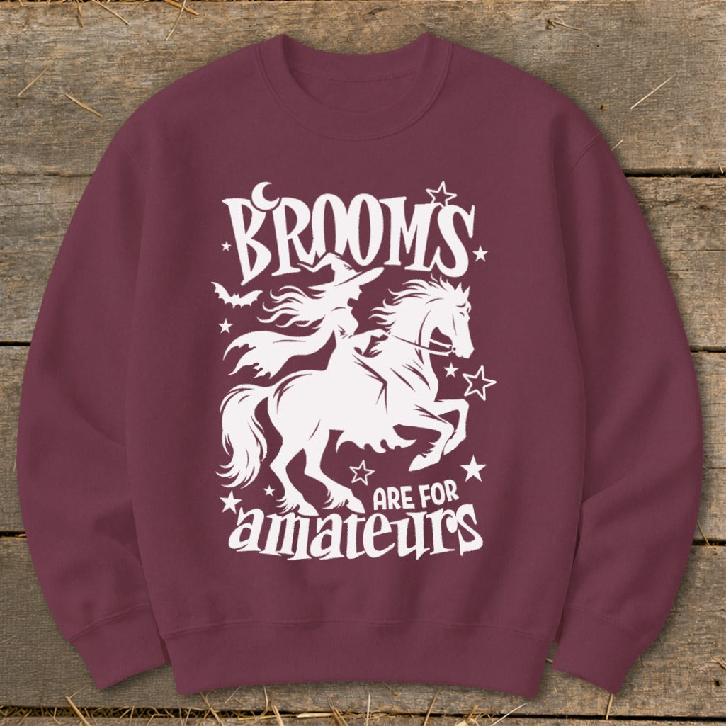 Maroon sweatshirt with white graphic: witch riding horse, "BROOMS ARE FOR AMATEURS" text.