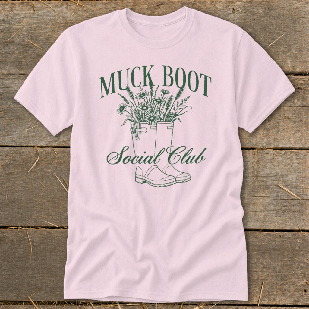 Pink t-shirt with green "Muck Boot Social Club" graphic featuring boots and flowers.