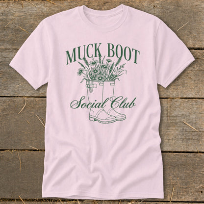 Pink t-shirt with green "Muck Boot Social Club" graphic featuring boots and flowers.