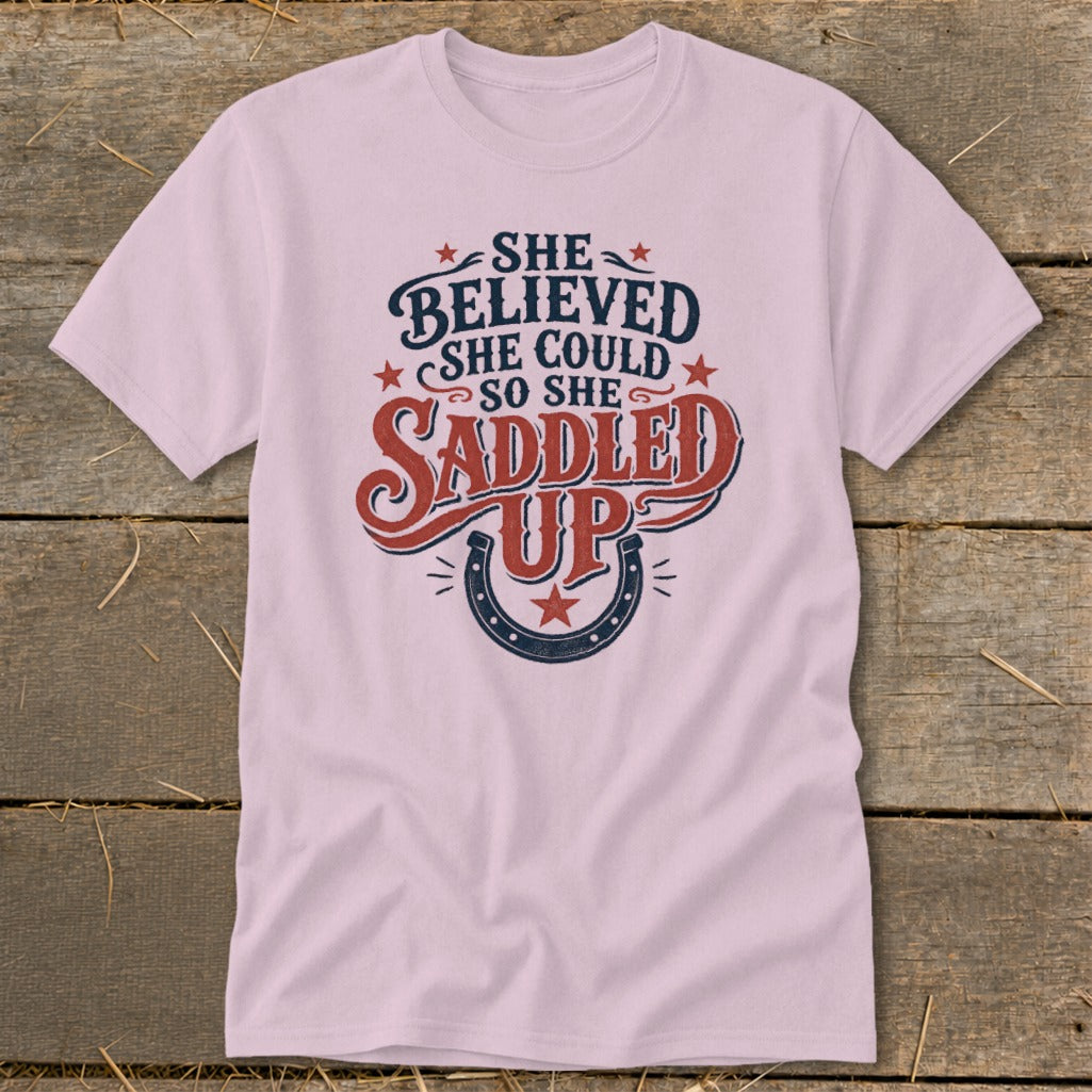 Pink t-shirt with "She Believed She Could So She Saddled Up" graphic and horseshoe.