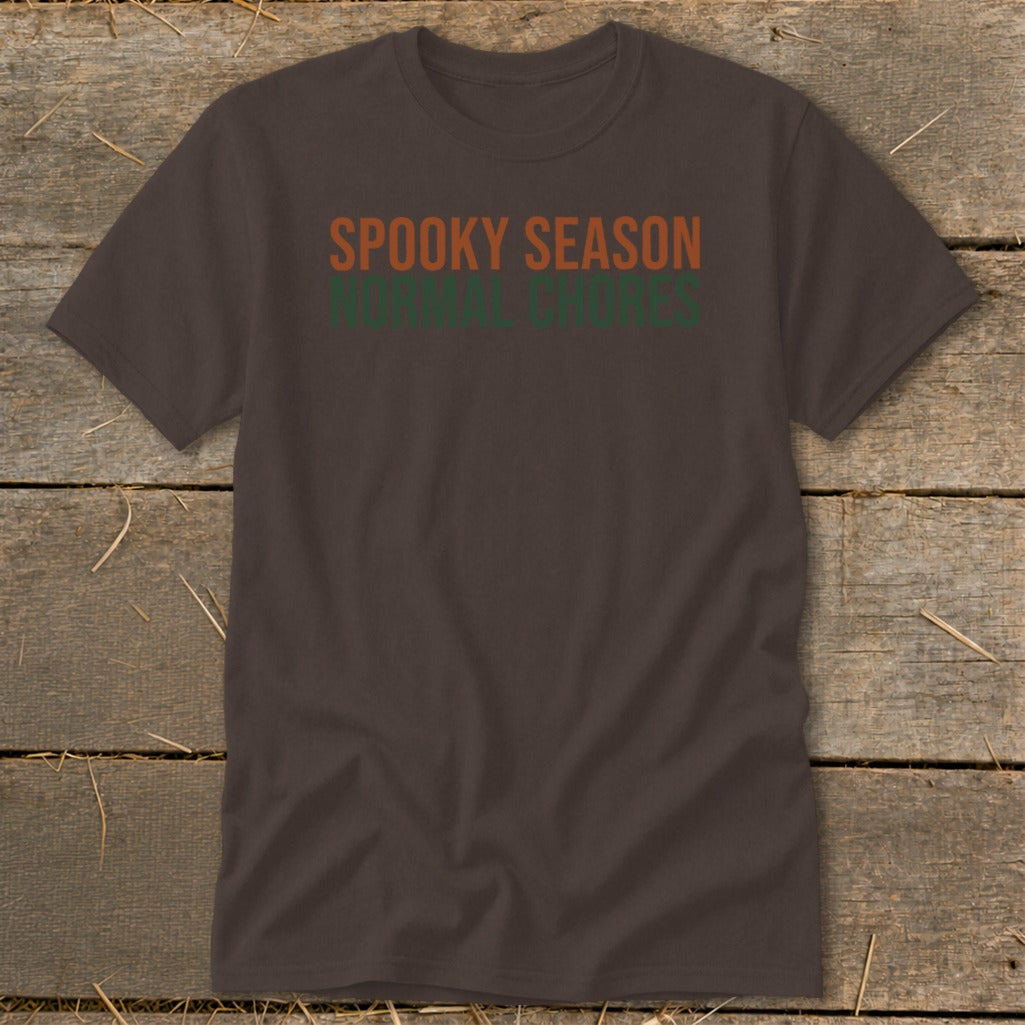 Brown t-shirt with orange text "SPOOKY SEASON" above green text "NORMAL CHORES".