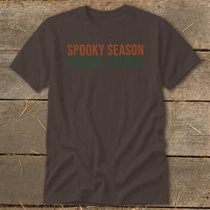 Brown t-shirt with orange text "SPOOKY SEASON" above green text "NORMAL CHORES".