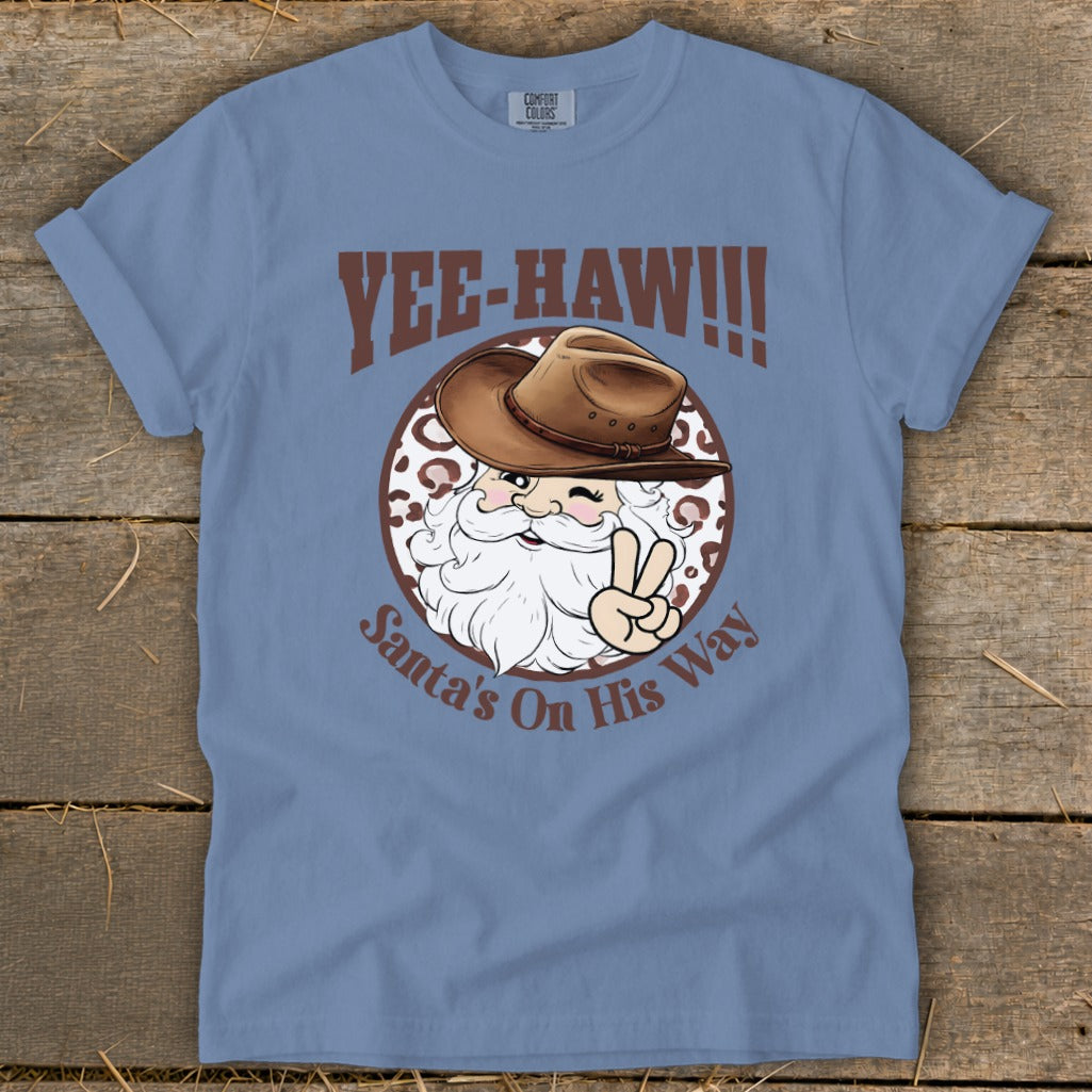 Blue t-shirt with Santa wearing a cowboy hat and giving a peace sign, text "Yee-Haw!!!" and "Santa's On His Way".