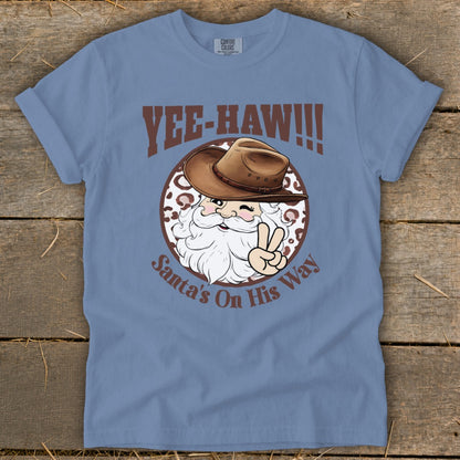 Blue t-shirt with Santa wearing a cowboy hat and giving a peace sign, text "Yee-Haw!!!" and "Santa's On His Way".