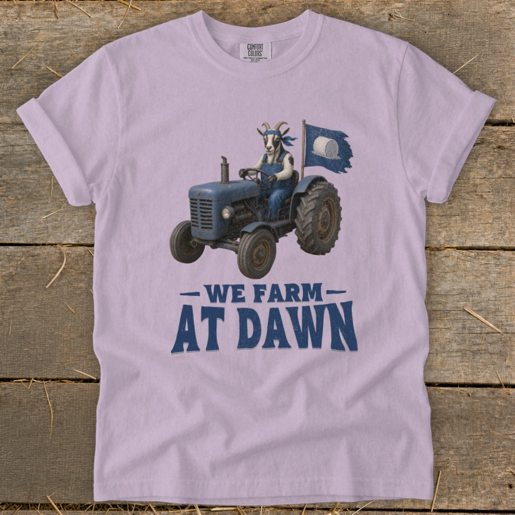 Goat in overalls driving a blue tractor with a "We Farm At Dawn" slogan.
