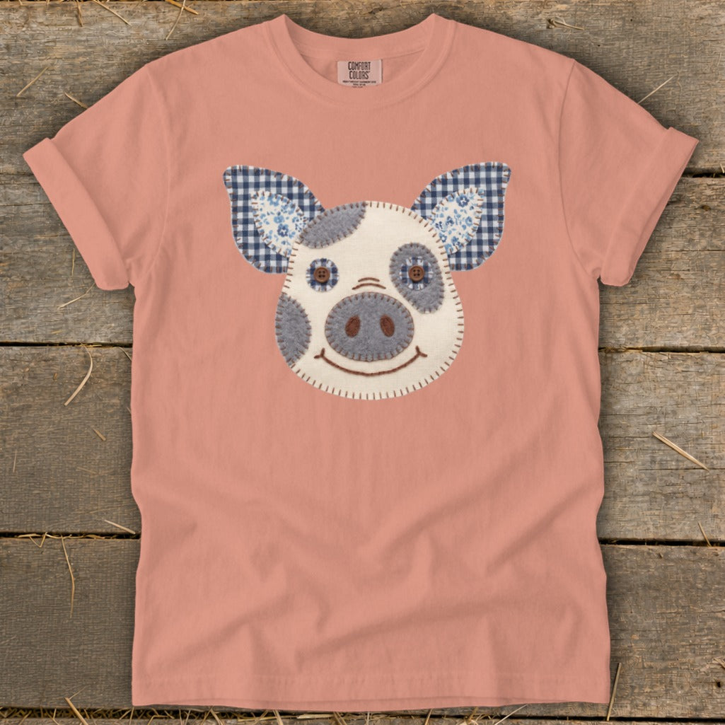 Peach t-shirt with a felt pig face applique and gingham ears.