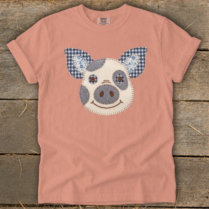 Peach t-shirt with a felt pig face applique and gingham ears.