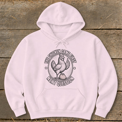 Pink hoodie with a graphic of a chicken on an egg and text "The chicken came first, next question."