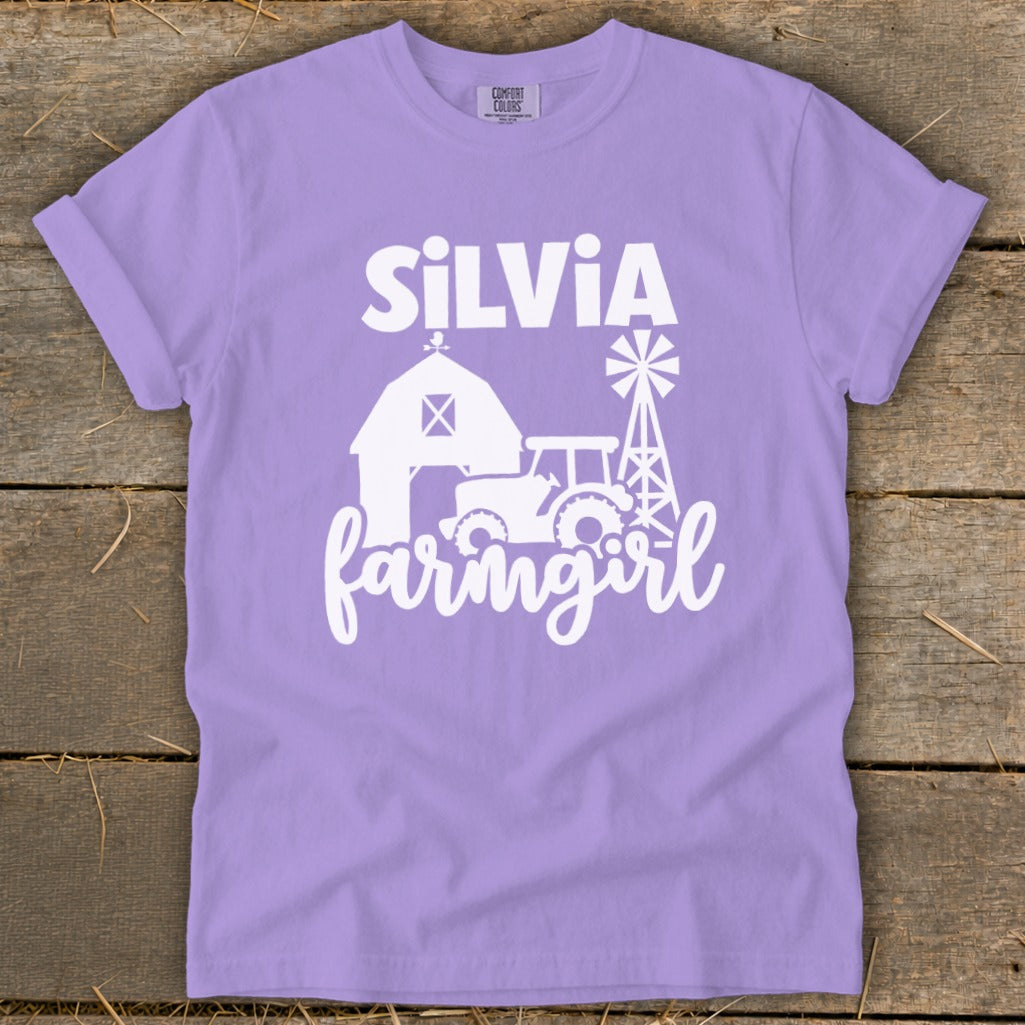 Purple t-shirt with white graphic of "SILVIA farmgirl" over barn, tractor, and windmill.