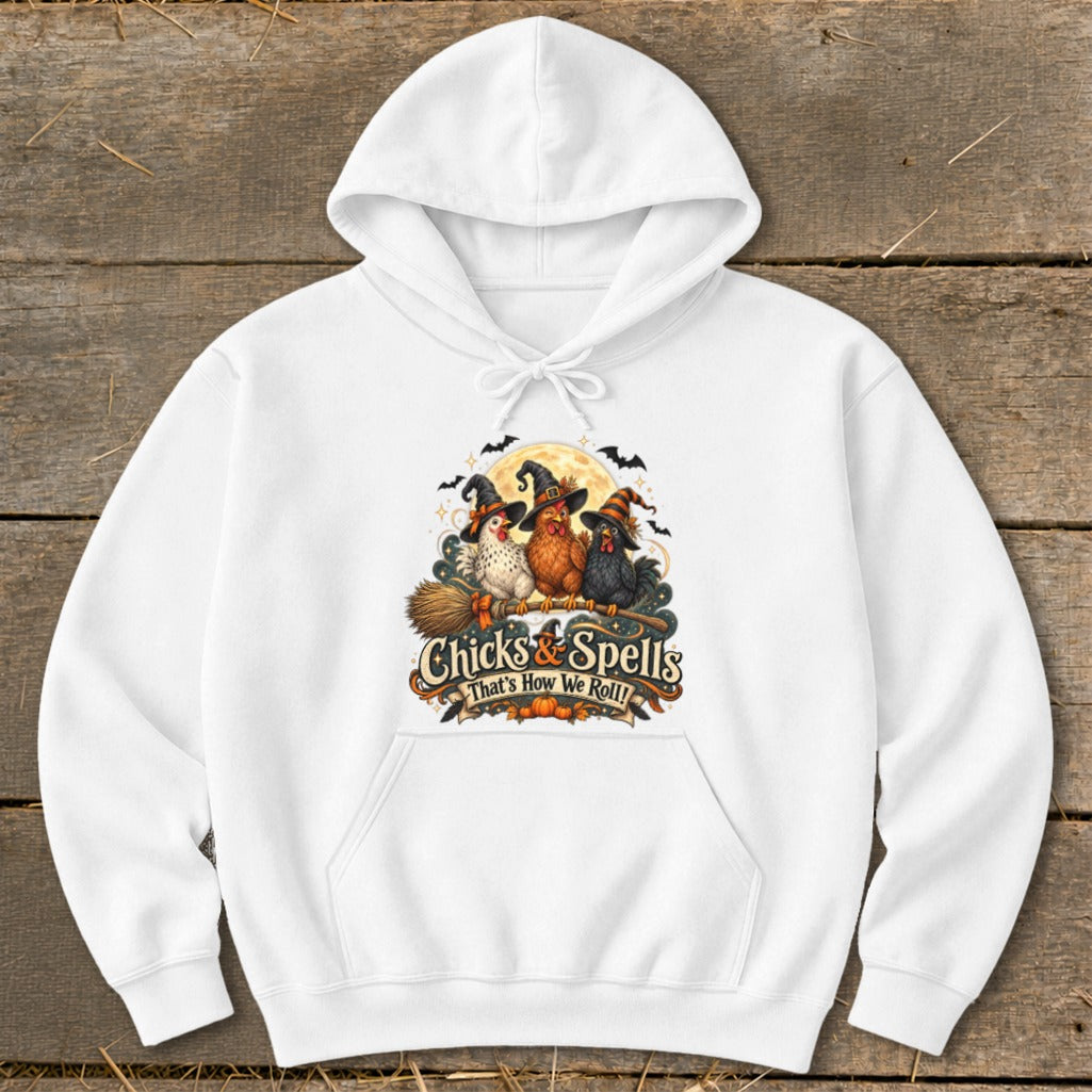 White hoodie with three witch chickens on a broom, "Chicks & Spells" text.