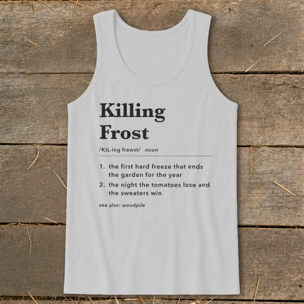 A light grey tank top printed with a humorous dictionary definition of a killing frost lies flat on a rustic wooden surface.