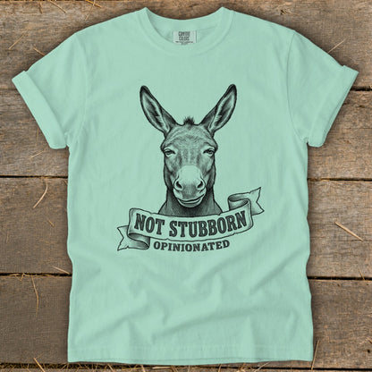 Mint t-shirt with black ink drawing of a donkey's head and "NOT STUBBORN OPINIONATED" text.
