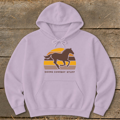 Light purple hoodie with a brown horse silhouette and sunset graphic reading "DOING COWBOY STUFF".