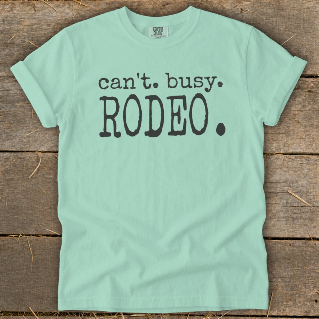 Light teal t-shirt with black text reading "can't. busy. RODEO."