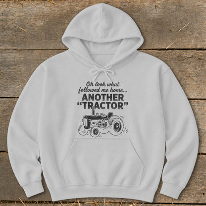 White hoodie with text "Oh look what followed me home... ANOTHER 'TRACTOR'" and tractor graphic.