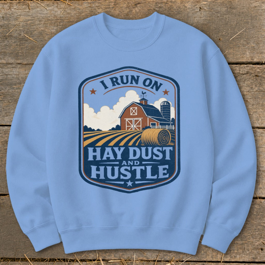 Light blue sweatshirt with a rural farm graphic and the text "I RUN ON HAY DUST AND HUSTLE".