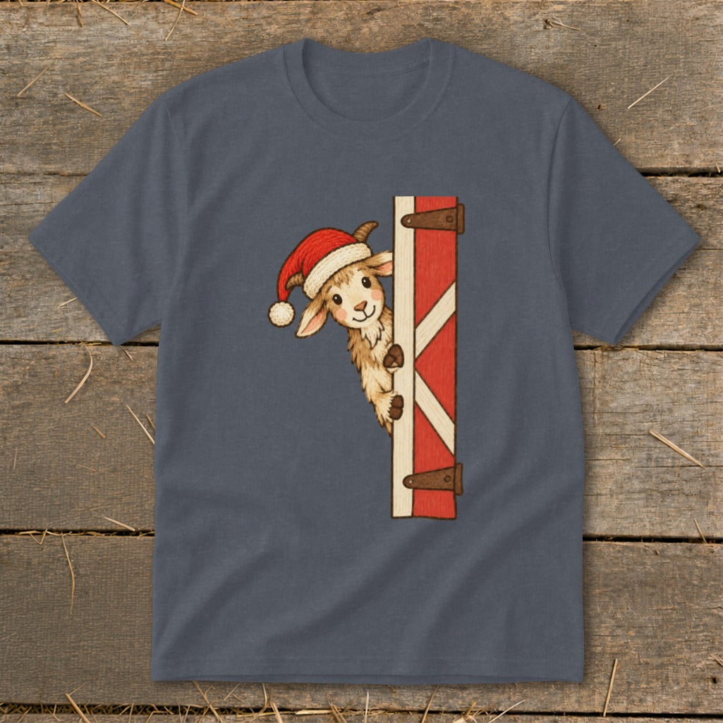 Goat wearing Santa hat peeking around a red barn door on a t-shirt.