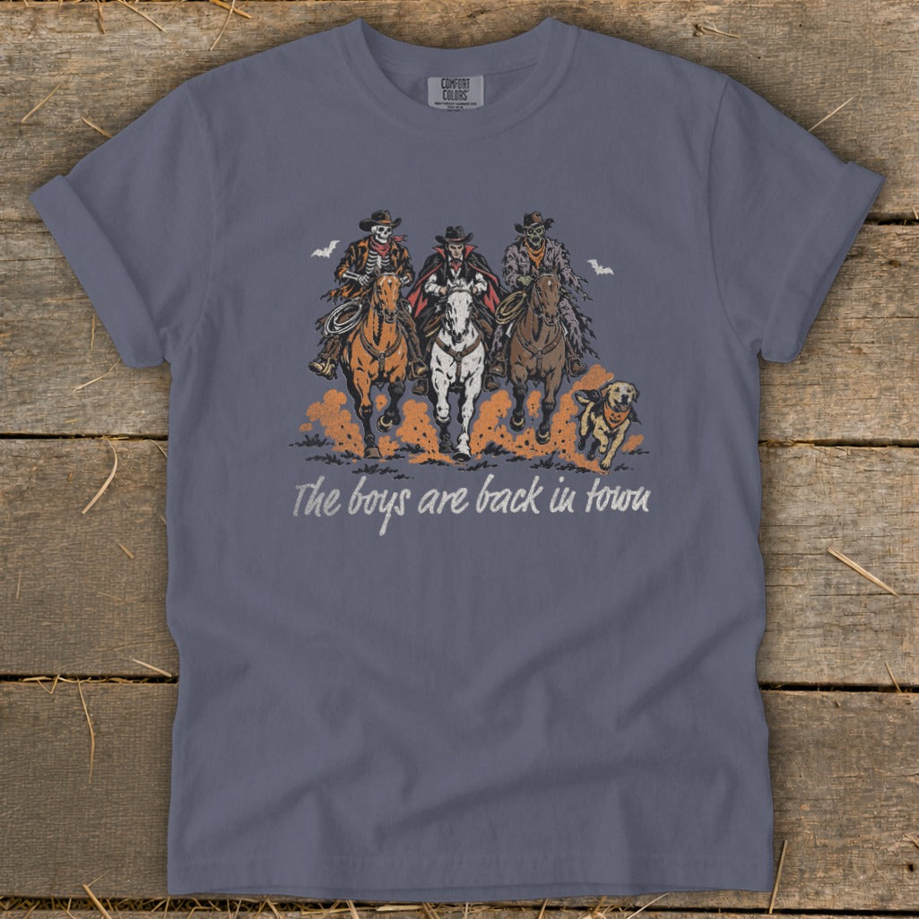 Skeleton, vampire, and zombie cowboys ride horses with a dog, text reads "The boys are back in town."