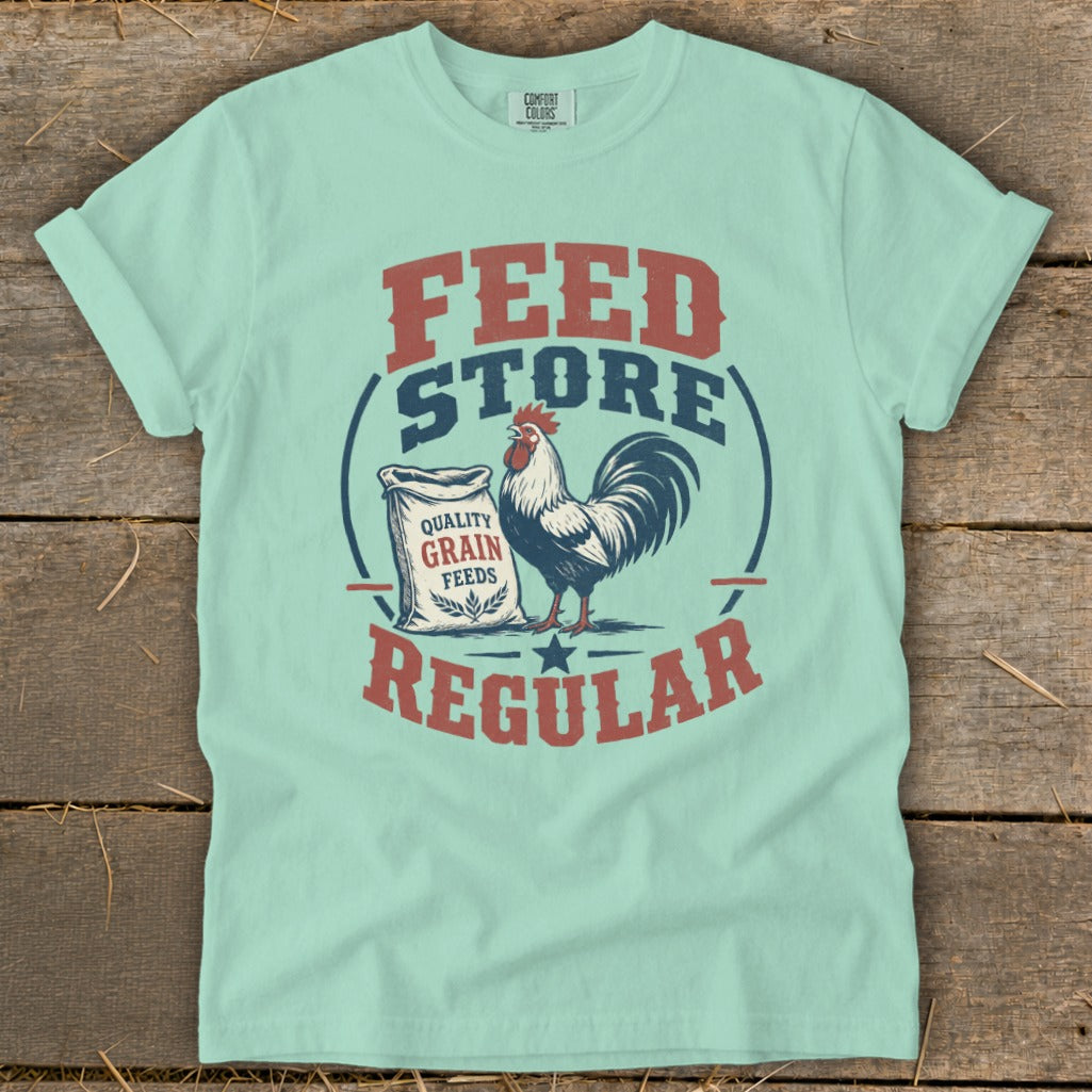 Light blue t-shirt with "Feed Store Regular" graphic, chicken, and grain bag.