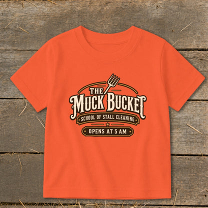 Orange t-shirt with "The Muck Bucket School of Stall Cleaning Opens at 5 AM" text.