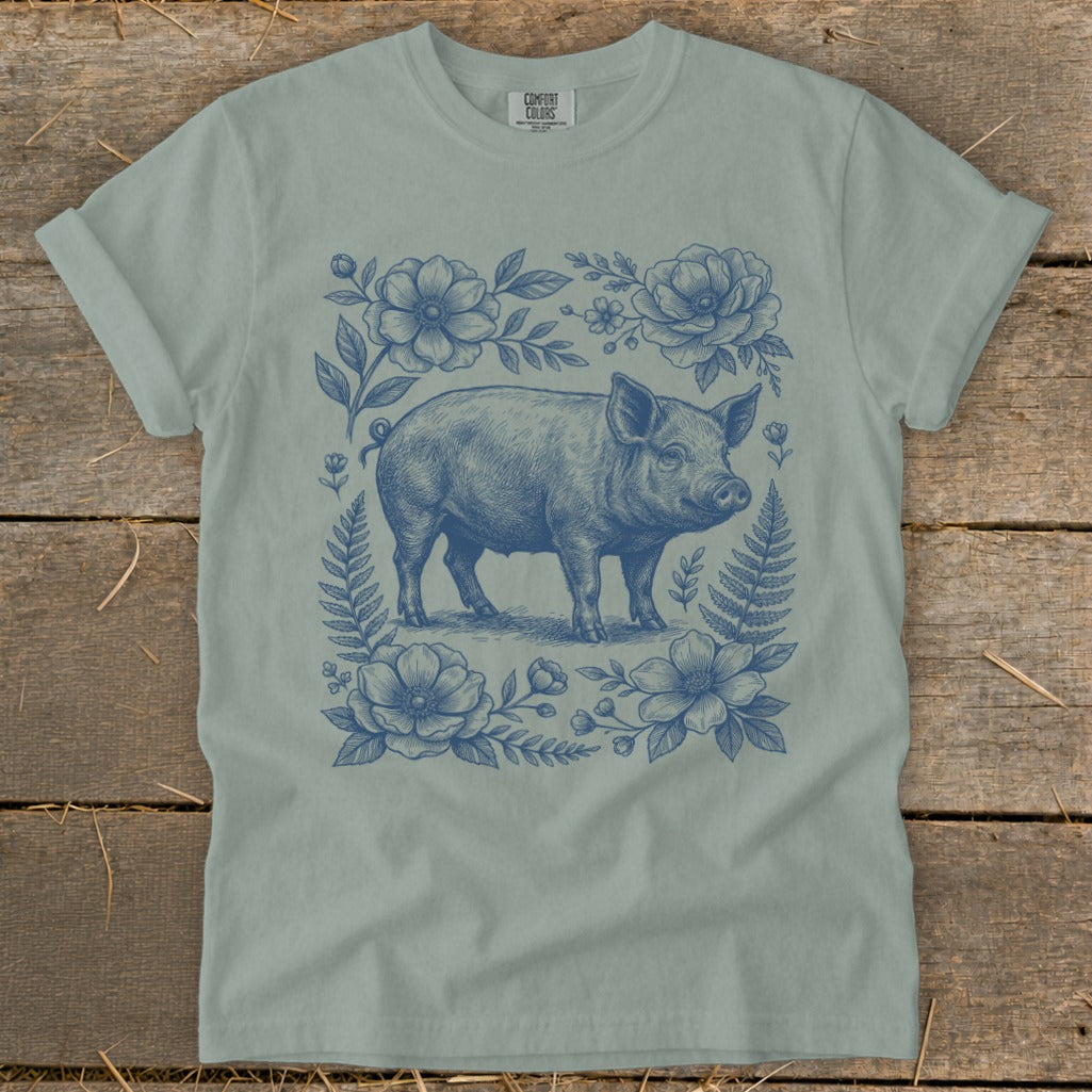T-shirt with blue line art of a pig surrounded by flowers and ferns.