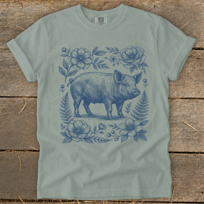 T-shirt with blue line art of a pig surrounded by flowers and ferns.