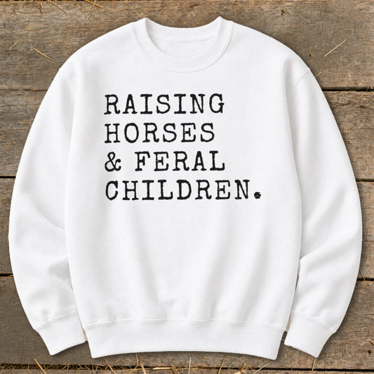 White sweatshirt with black typewriter text: Raising Horses & Feral Children.