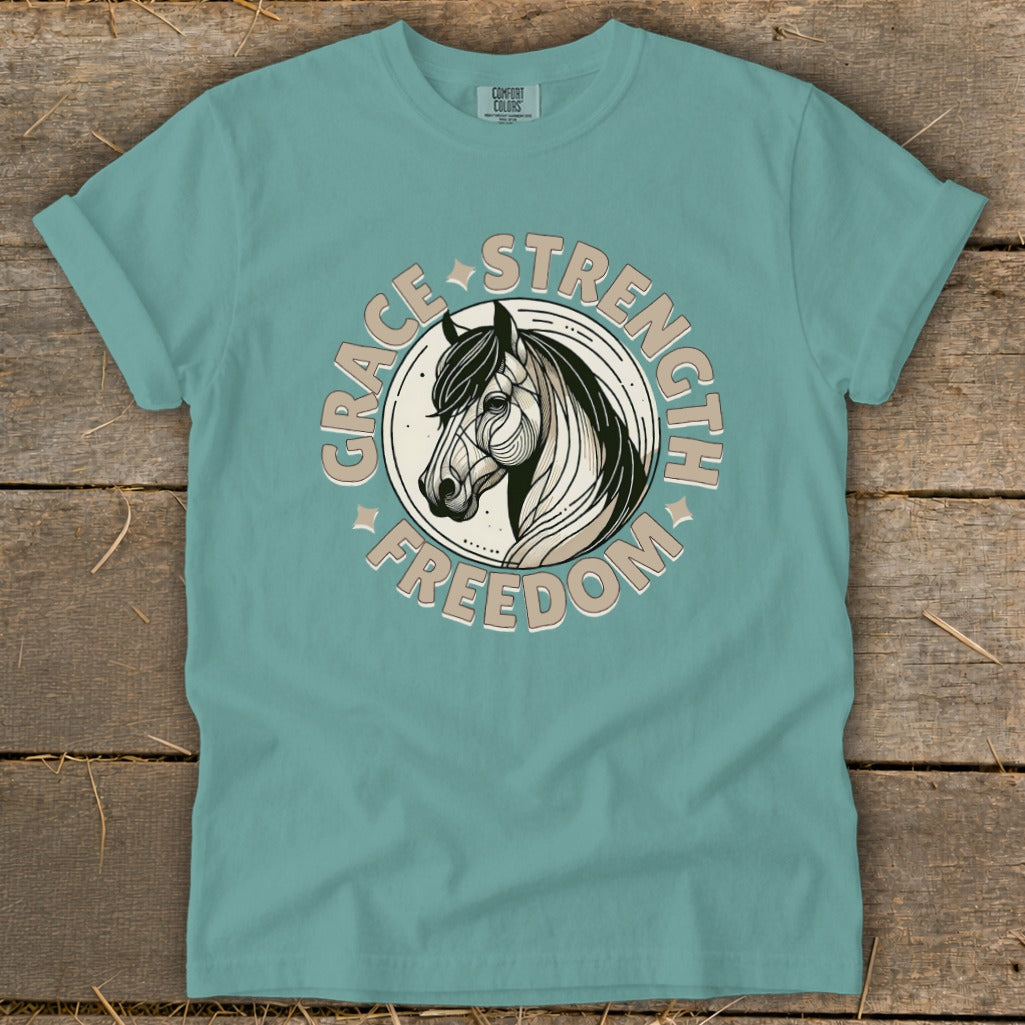 Teal t-shirt with a circular graphic of a horse head and text "GRACE STRENGTH FREEDOM."